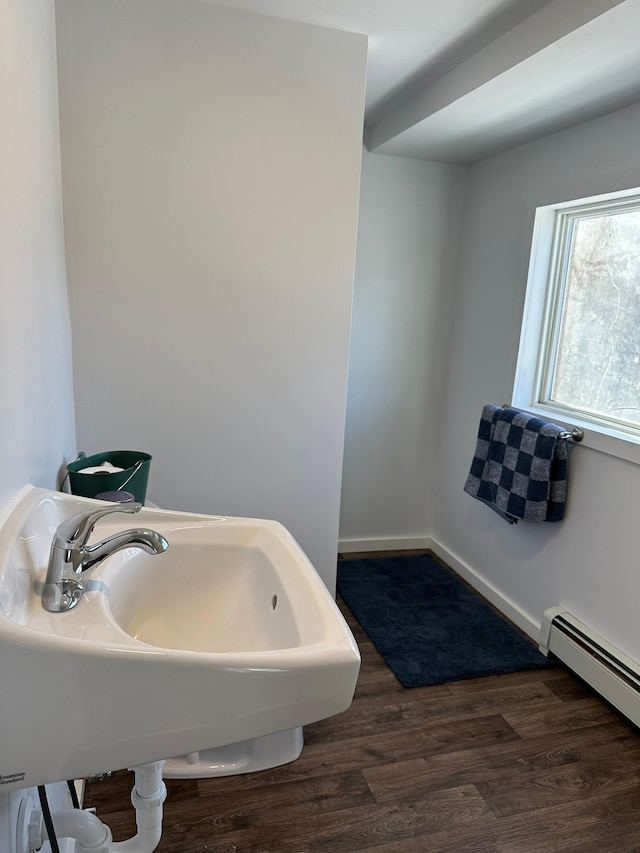 bathroom with baseboards, a sink, baseboard heating, and wood finished floors