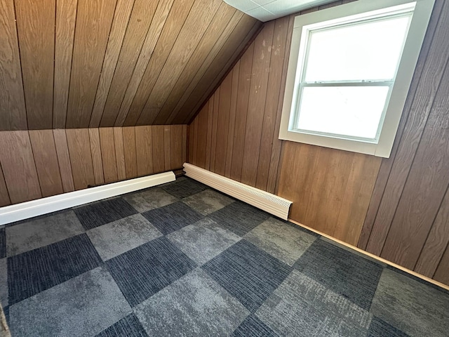 bonus room featuring vaulted ceiling, a baseboard heating unit, and wooden walls