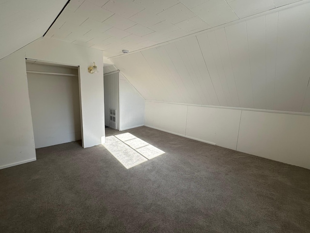 bonus room featuring lofted ceiling and dark colored carpet