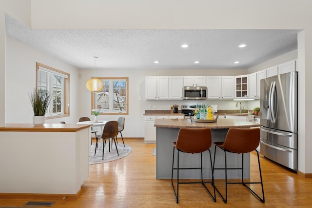 11767 36th Cir NE, Saint Michael, MN 55376 - kitchen with appliances with stainless steel finishes, white cabinetry, a kitchen bar, glass insert cabinets, and a center island