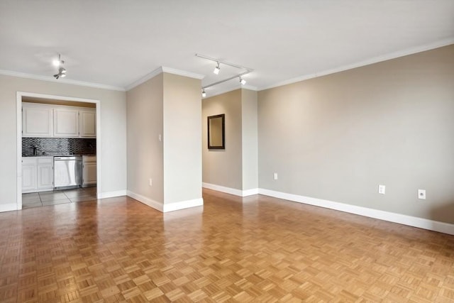 spare room with ornamental molding, track lighting, and baseboards