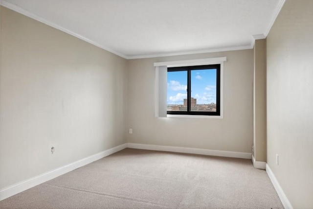 spare room with ornamental molding, light colored carpet, and baseboards