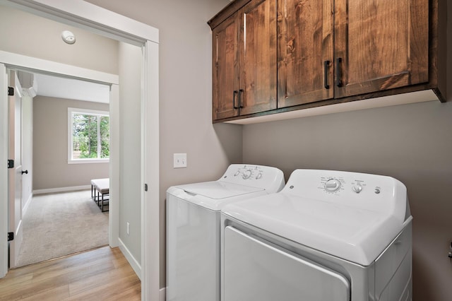 washroom with cabinets, independent washer and dryer, and light hardwood / wood-style flooring