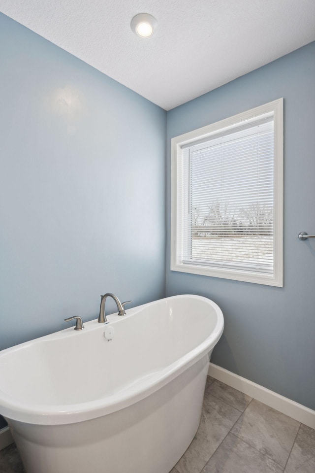 bathroom with tile patterned flooring, a bathtub, and a textured ceiling