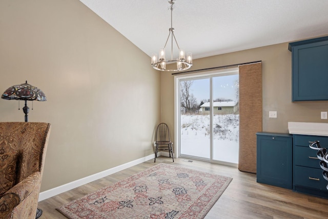 dining area with an inviting chandelier, lofted ceiling, and light wood-type flooring