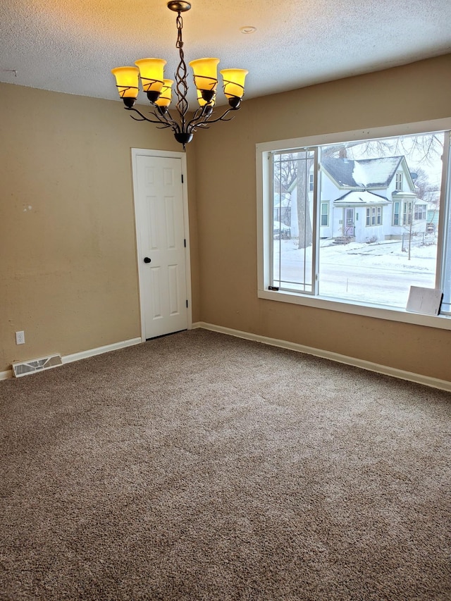 carpeted empty room with a textured ceiling and an inviting chandelier