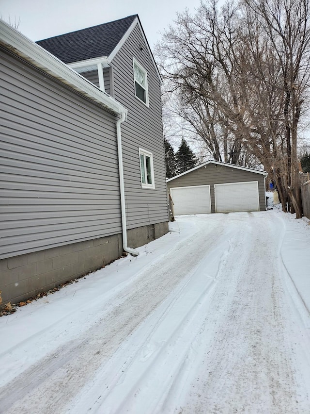 view of snow covered exterior featuring a garage and an outdoor structure