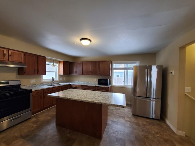 kitchen featuring stainless steel appliances, a center island, sink, and light stone counters