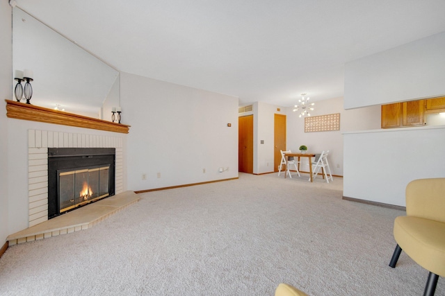 unfurnished living room featuring a chandelier, carpet, a brick fireplace, and baseboards