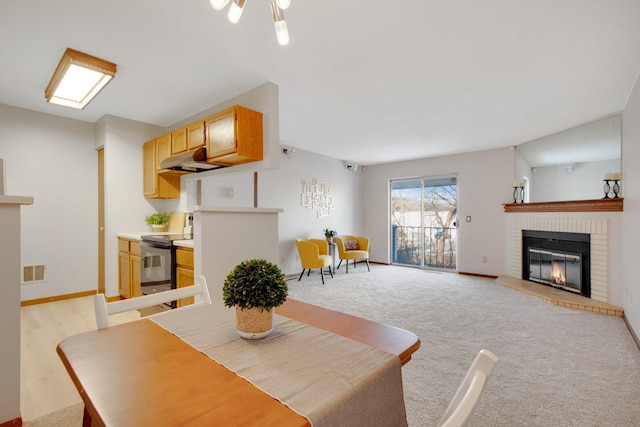 dining area featuring light carpet, baseboards, a fireplace, and visible vents