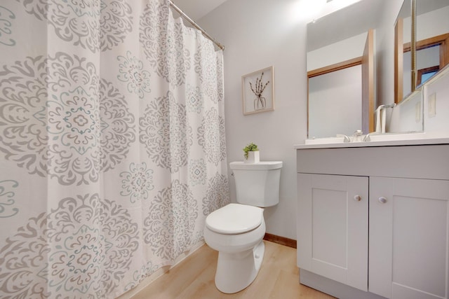 bathroom with baseboards, toilet, wood finished floors, curtained shower, and vanity