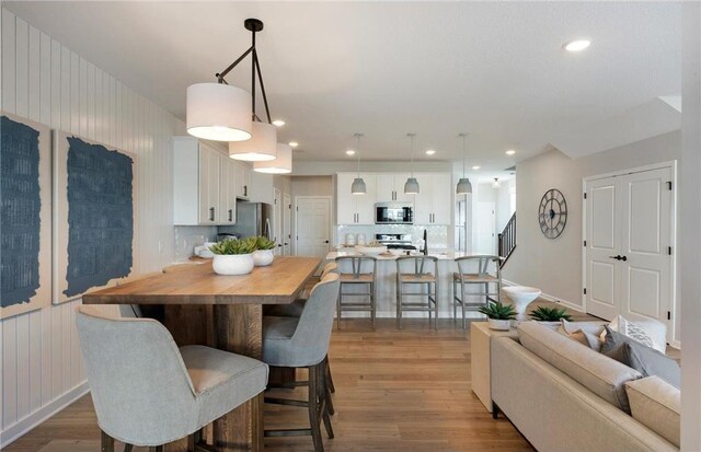 dining area featuring stairs, recessed lighting, baseboards, and wood finished floors