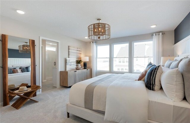bedroom with light colored carpet, recessed lighting, connected bathroom, and a notable chandelier