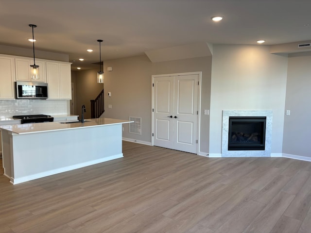 kitchen with visible vents, a sink, stainless steel microwave, recessed lighting, and light wood-style flooring