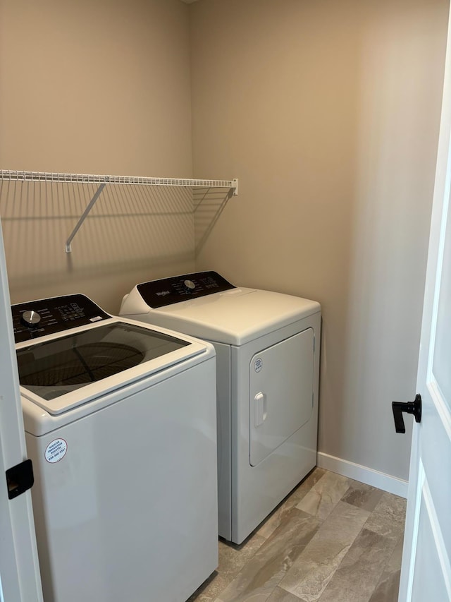 clothes washing area featuring separate washer and dryer, baseboards, and laundry area