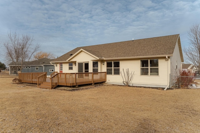 rear view of property featuring a wooden deck and a lawn