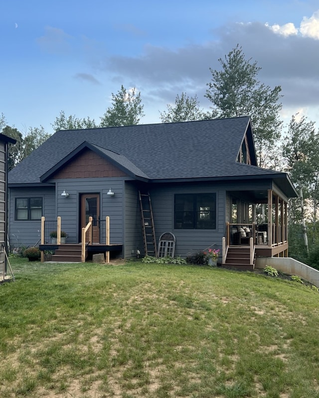 view of front of house with roof with shingles and a front yard
