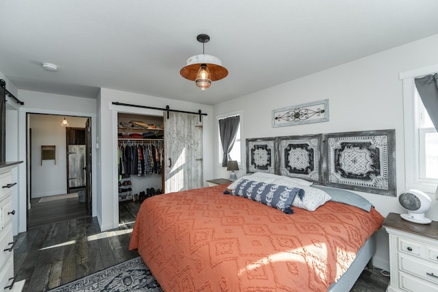 bedroom with dark wood-style flooring, a spacious closet, a barn door, and a closet