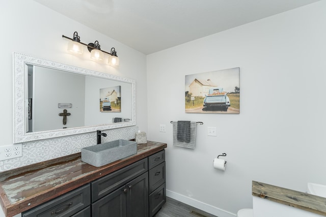 bathroom with baseboards, vanity, toilet, and wood finished floors