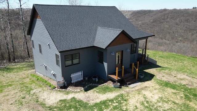 view of side of home featuring roof with shingles and a yard