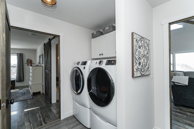 laundry area featuring cabinet space, a barn door, separate washer and dryer, baseboards, and dark wood-style floors
