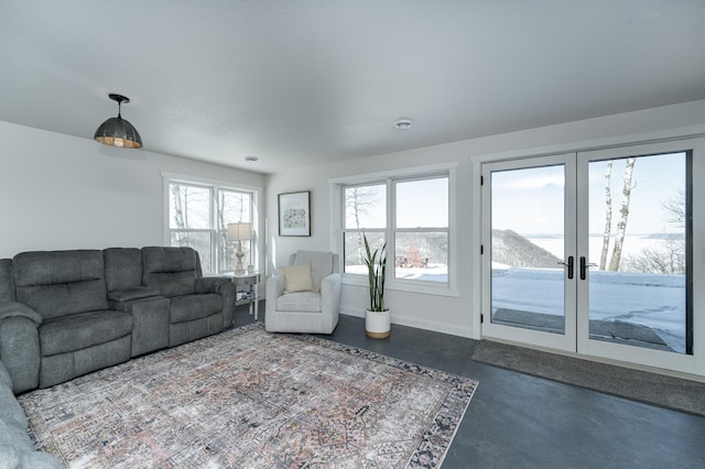living area with baseboards, french doors, and finished concrete floors
