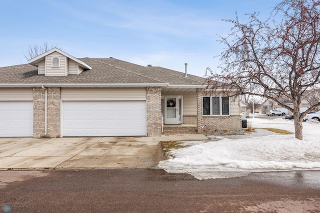 view of front of home with a shingled roof, concrete driveway, brick siding, and an attached garage