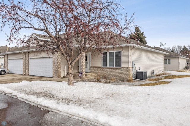 view of front of house with a garage, cooling unit, brick siding, and driveway