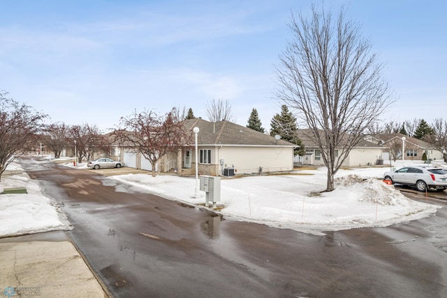 view of front of home featuring driveway, central AC, an attached garage, and a residential view