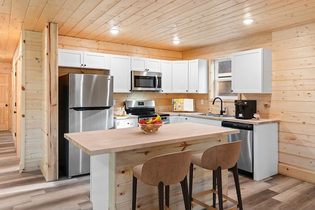 kitchen featuring sink, wood ceiling, appliances with stainless steel finishes, white cabinetry, and a kitchen breakfast bar