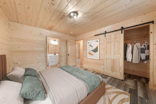 bedroom with wood ceiling, wood-type flooring, wooden walls, and a barn door