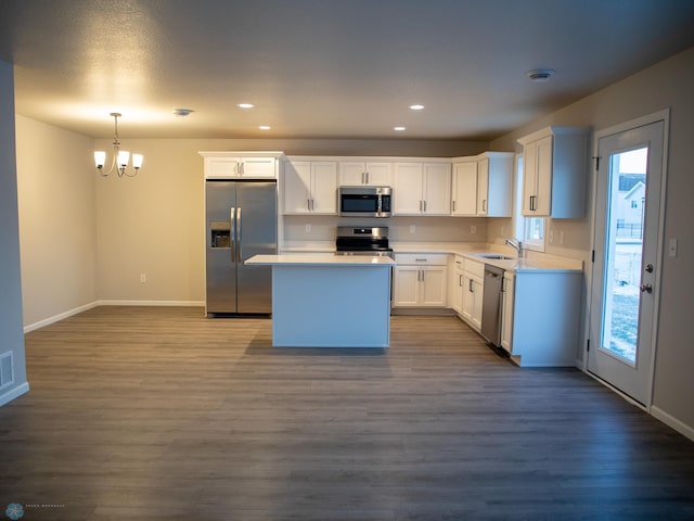 kitchen featuring sink, hanging light fixtures, dark hardwood / wood-style floors, stainless steel appliances, and white cabinets