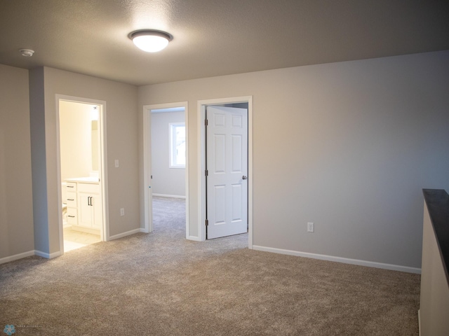 unfurnished bedroom featuring carpet, connected bathroom, and a textured ceiling