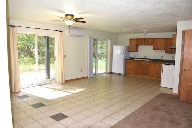 kitchen featuring a healthy amount of sunlight, white appliances, a wall mounted air conditioner, and sink