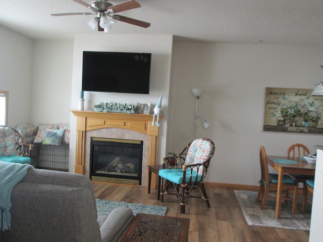 1902 Tiffany Cove Ln SW, Rochester, MN 55902 - living room featuring wood finished floors, a tile fireplace, ceiling fan, a textured ceiling, and baseboards