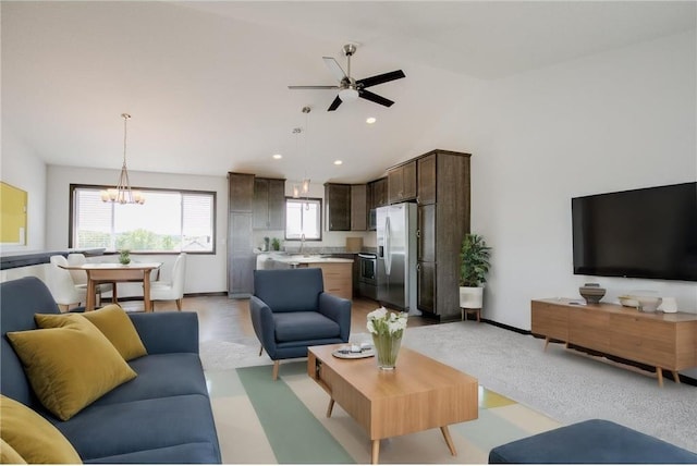 living room featuring vaulted ceiling, sink, and ceiling fan with notable chandelier