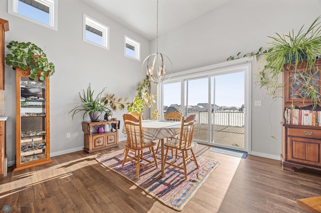 dining space featuring a towering ceiling, plenty of natural light, dark hardwood / wood-style flooring, and a chandelier