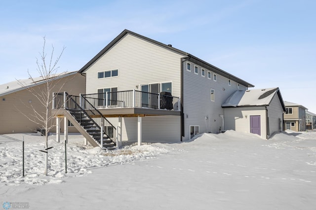 snow covered back of property with a deck