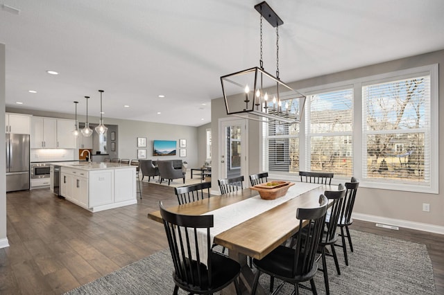 dining space with dark hardwood / wood-style floors, sink, and a notable chandelier