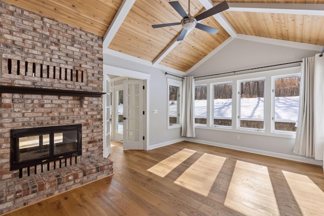 unfurnished living room with a brick fireplace, baseboards, vaulted ceiling with beams, and hardwood / wood-style floors