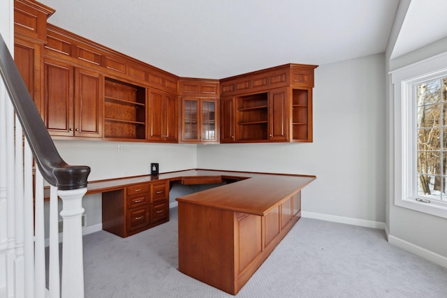 office space featuring light carpet, plenty of natural light, built in desk, and baseboards