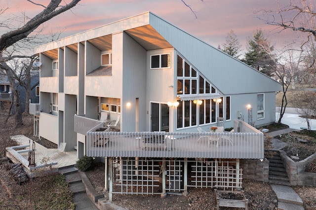 back of house at dusk featuring a deck