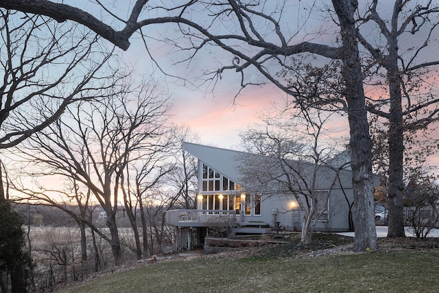 back of property at dusk featuring a sunroom, a wooden deck, and a yard