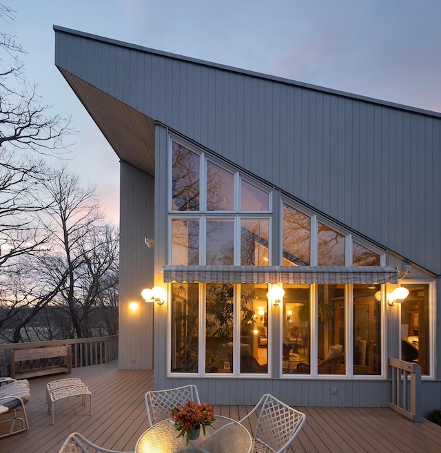 back of property at dusk with a wooden deck