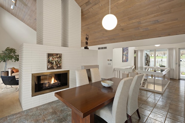 dining space featuring stone tile floors, high vaulted ceiling, visible vents, and wood ceiling