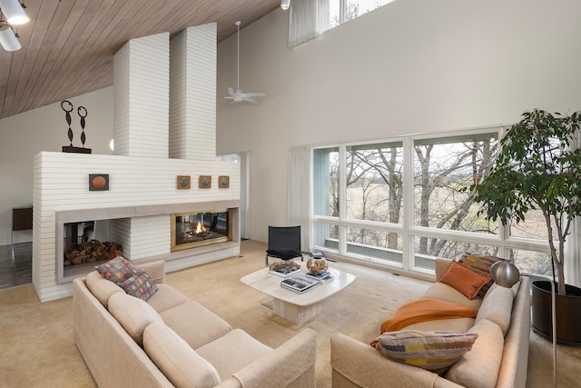 living room featuring carpet, a ceiling fan, a large fireplace, and high vaulted ceiling