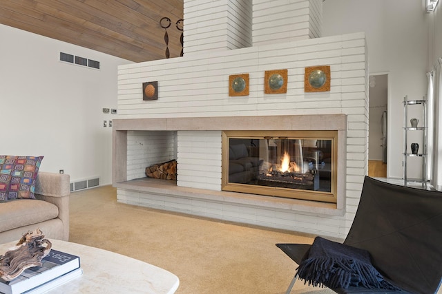 living room featuring a glass covered fireplace, visible vents, and carpet flooring