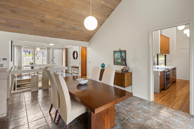dining area featuring wood ceiling, stone finish flooring, plenty of natural light, and high vaulted ceiling