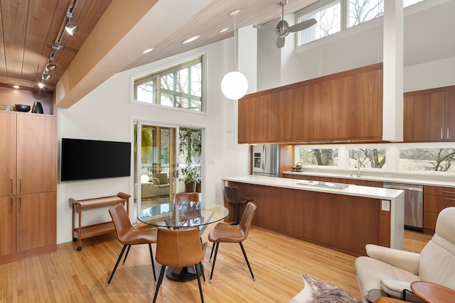 dining area with wood ceiling, rail lighting, light wood-style flooring, and a healthy amount of sunlight