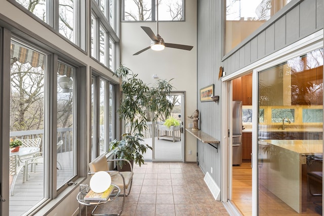 sunroom with a towering ceiling, a sink, and tile patterned floors